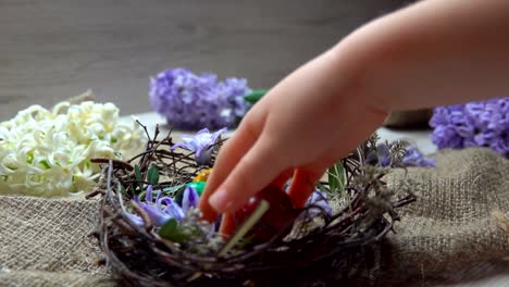 Child's-hand-lays-colored-egg-in-in-the-Easter-nest