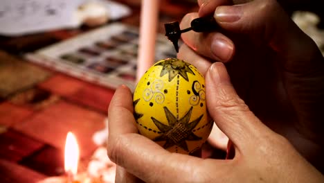 manos-de-artesano-femenino-pintando-el-proceso-folclórico-de-huevo-de-Pascua-creando-capa-por-capa-con-la-cera-y-usando-pinturas-multicolor-de-cerca