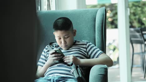 Young-teenager-playing-game-on-smartphone-in-cafe