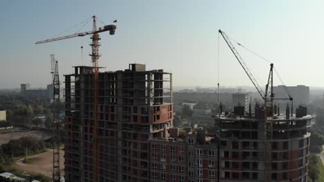 An-aerial-view-of-a-residential-building-in-construction.-Tower-cranes-working-by-the-building.-4K