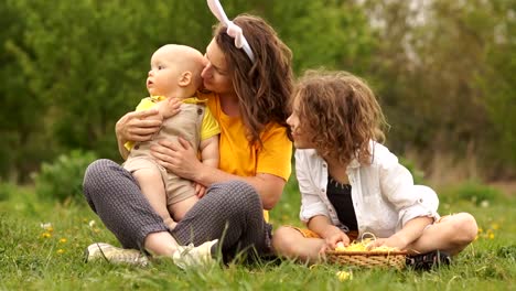 Schöne-Familie-umarmt-im-Park-bei-einem-Picknick.-Fröhliche-Osterfamilie.-Mama-und-zwei-Söhne.-Muttertag