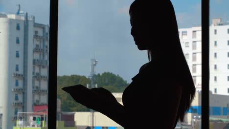 Frau-mit-Tablet-am-Fenster