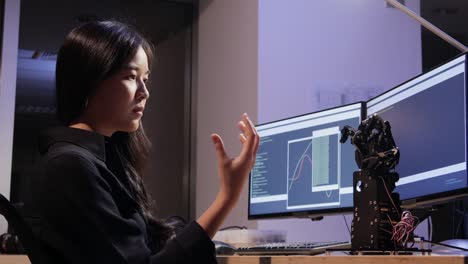 Asian-testing-cyborg-hand-at-control-room.-Female-doing-her-robot-project-she-testing-sensor-signal.-Technology-and-innovation-concept.