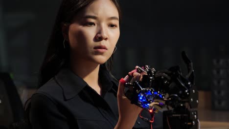 Asian-testing-cyborg-hand-at-control-room.-Female-doing-her-robot-project-she-testing-sensor-signal.-Technology-and-innovation-concept.