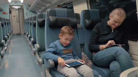 Familia-viajando-en-tren-y-entretenido-con-electrónica