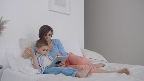 Happy-family-mother-and-child-son-with-tablet-in-evening.-Happy-family-mother-and-child-son-with-tablet-in-evening-before-bed.