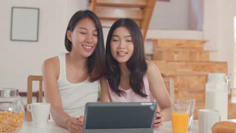 Asian-Lesbian-influencer-couple-using-tablet-record-vlog-video-on-social-media-while-having-breakfast-in-kitchen.