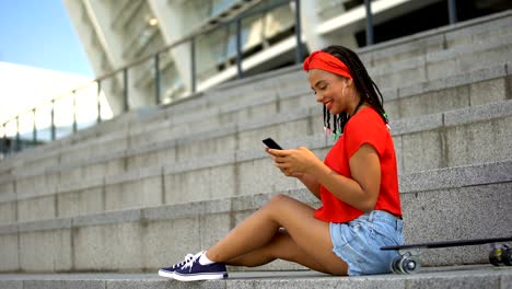 Pretty-mixed-race-teenager-chatting-with-friends-in-social-networks-and-smiling