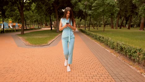 young-caucasian-woman-scrolling-news-feed-walking-on-the-street-in-city-park