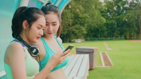 Lifestyle-asiatische-Sportfrauen-halten-Smartphone-spielen-Musik-Entspannung