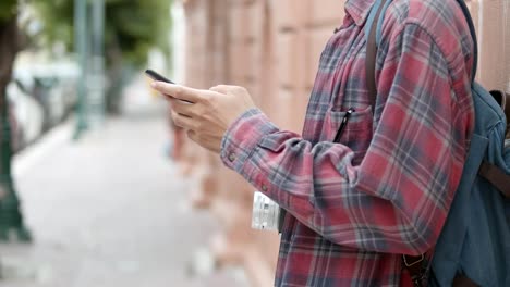 Close-up-hands-tourists-Asian-man-using-a-smartphone-checking-social-media-while-standing-beside-the-street-in-Thailand.-Young-Asian-man-blogger-happy-enjoying-leisure-lifestyle-travel.