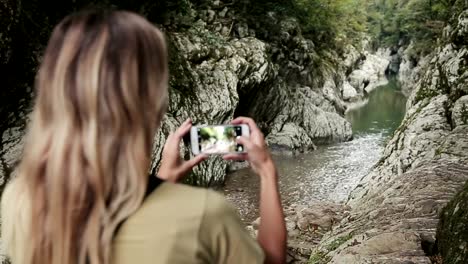 Eine-Frau-fotografiert-einen-Bergfluss-in-einer-Felsspalte