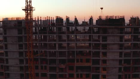 Aerial-Shot-of-the-Building-in-the-Process-of-Construction.-Labor-working-in-big-construction-site.-In-the-Background-Working-Crane-and-city