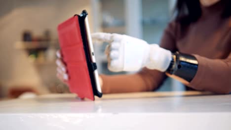 Person-types-on-a-tablet-with-bionic-hand,-close-up.