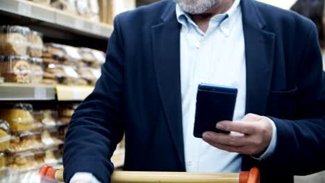 Beschnittene-Aufnahme-von-Mann-mit-Smartphone-im-Supermarkt