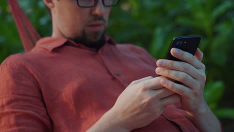 Mann-tippt-am-Smartphone-im-Garten