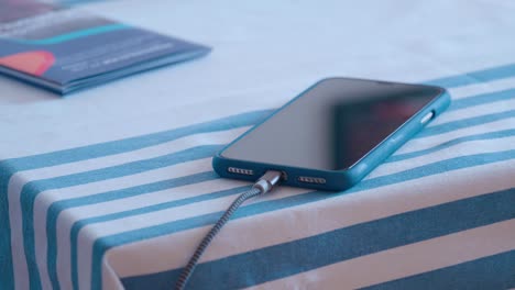 Smartphone-on-kitchen-table-with-charging-cable-being-plugged-and-unplugged