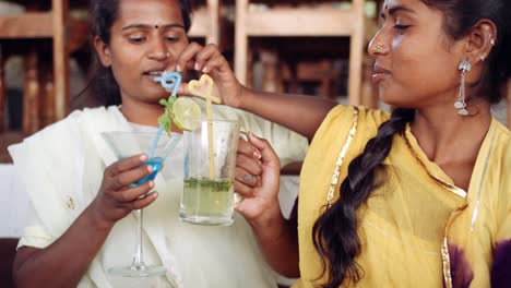 Two-women-chilling-sipping-drinks-using-technology-in-cafe