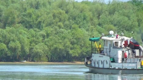 The-cargo-barge-is-floating-on-the-lake.-A-small-cargo-ship-with-a-crane-on-board