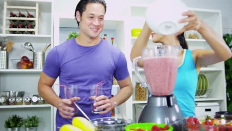 Ethnic-male-female-using-kitchen-blender-fresh-juice