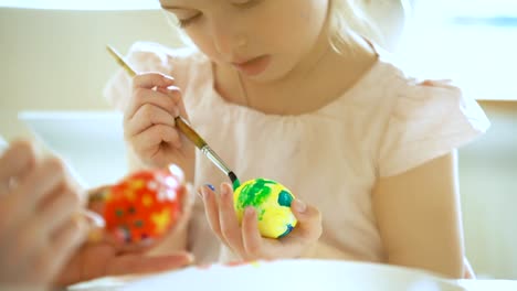 Joven-madre-y-su-pequeña-hija-con-orejas-de-conejo-para-colorear-huevos-de-Pascua