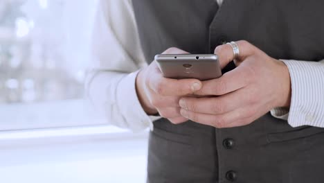 Smartly-dressed-man-holding-smartphone-in-hands,-scrolling-social-media-newsfeed