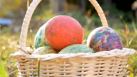 Close-up-of-basket-with-colourful-a-easter-eggs-on-grass-in-sunshine-background