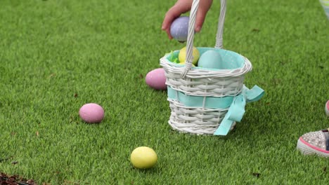 Young-girl-picking-up-Easter-eggs-in-grass-and-putting-them-into-basket