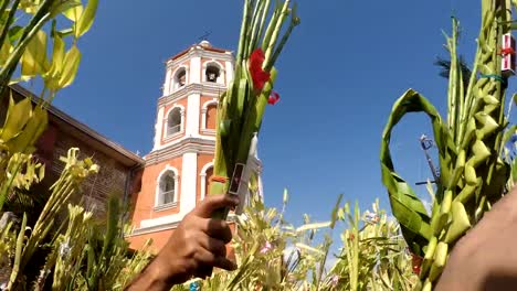 Menschen-Welle-Kokospalme-verlässt-am-Palmsonntag-Feier.-Das-fest-erinnert-an-den-triumphalen-Einzug-Jesu-in-Jerusalem.-Kirchturm-Hintergrund