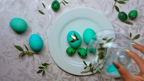 Hand-removes-a-glass-dome-from-a-plate-with-green-easter-eggs