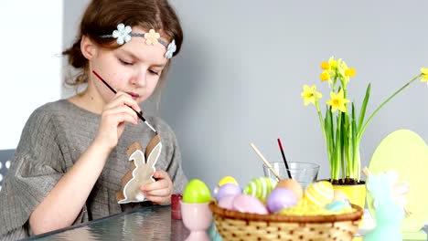 Ein-süßes-Mädchen-bereitet-sich-auf-Ostern,-malt-der-Osterhase.-Auf-dem-Tisch-liegt-ein-Osternest