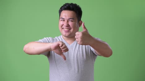 Young-handsome-overweight-Asian-man-against-green-background