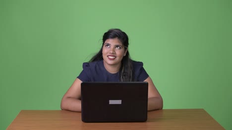 Young-overweight-beautiful-Indian-businesswoman-against-green-background