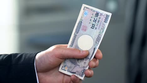 Male-hands-counting-money,-exchanging-Japanese-yen-at-bank-branch,-finance