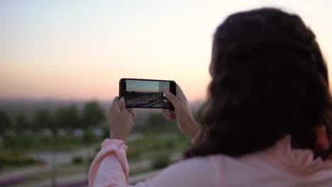 A-girl-with-long-hair-takes-a-photo-of-the-city-using-a-smartphone.-slow-motion