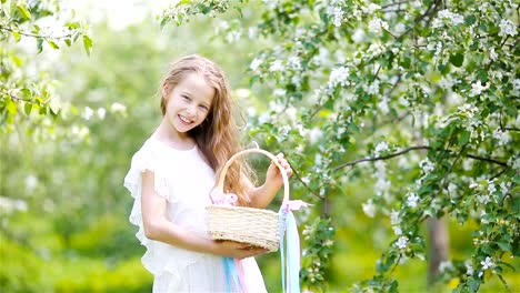 Entzückende-kleine-Mädchen-in-blühender-Apfelgarten-an-schönen-Frühlingstag