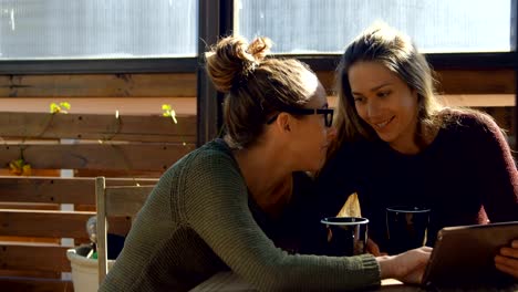 Lesbian-couple-interacting-with-each-other-at-cafe-4k