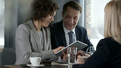 Geschäftspartnern-Ideen-zu-diskutieren-und-mit-Tablet-an-Kaffee-Pause-im-Cafe