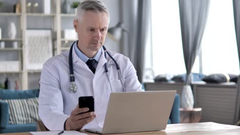 Arzt-arbeiten-am-Laptop-und-Smartphone-in-Klinik