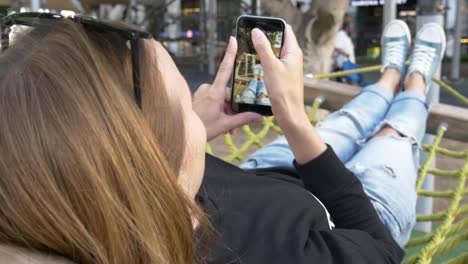 tener-descanso-en-la-hamaca-de-la-ciudad,-mujer-tomar-selfie-de-las-piernas