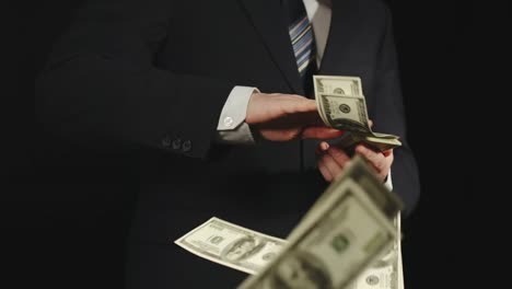 SLOW-MOTION:-Businessman-in-strict--suit-throws-bundle-of-US-dollar-bills-one-by-one---Front-View,