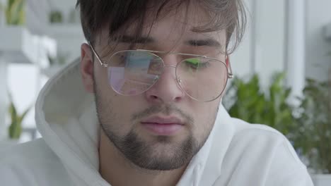 Close-up-retrato-joven-atractivo-chico-en-gafas-sentado-en-el-centro-o-restaurante-y-wotking-en-el-ordenador-portátil