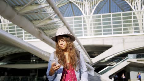 Mujer-sonriente-usando-teléfono-inteligente-en-la-estación-de-tren