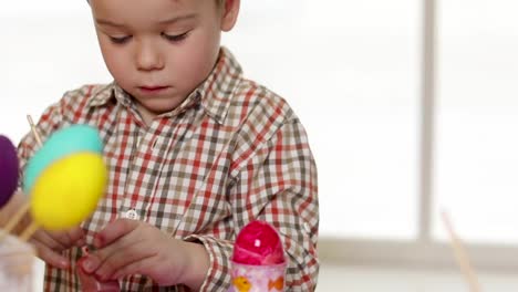 Niño-feliz-vistiendo-orejas-de-conejo-pintando-huevos-el-día-de-Pascua.