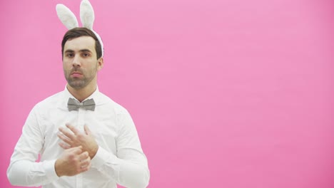 Young-handsome-man-standing-on-a-pink-background.-Having-adjusted-exactly-the-butterfly-on-the-shirt,-and-the-sleeves.-Putting-a-hand-on-hand-after-some-time-shows-the-class-and-goes-from-the-frame.