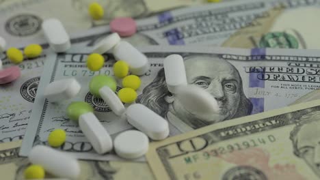 Pills-falling-on-dollar-banknotes,-expensive-medication,-pharmaceutical-business