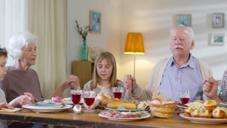 Familie-hält-Hände-und-betet-vor-dem-Abendessen