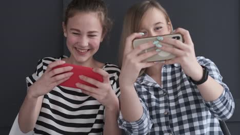 Teenage-girls-playing-game-on-mobile-phones