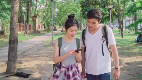 Slow-motion---Traveler-Asian-couple-direction-on-location-map-in-Bangkok,-Thailand,-couple-using-mobile-phone-looking-on-map-find-landmark-while-spending-holiday-trip.-Lifestyle-couple-travel-concept.