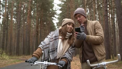 Pareja-con-bicicletas-usando-smartphone-en-Park